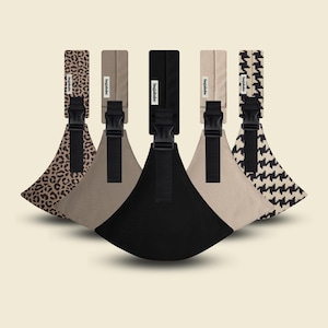 May include: Five baby carrier hip seats in various patterns and colors. The carriers include a leopard print, tan, black, beige, and a black and white houndstooth pattern. Each carrier has a black buckle and a rectangular strap with the brand name.