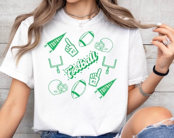 Peut inclure: T-shirt blanc avec un motif vert sur le thème du football. Le motif comprend des ballons de football, des casques, des poteaux de but et un symbole de la main avec le numéro un. Le mot "Football" est écrit en police script.