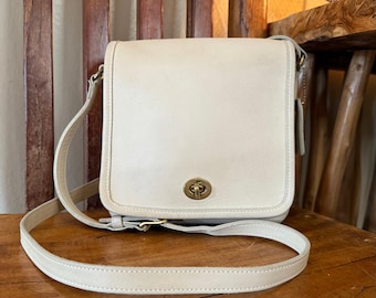 Bolso bandolera Coach Vintage Companion de piel color crema con solapa.