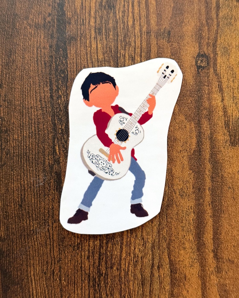 K&ouml;nnte beinhalten: Ein Aufkleber mit einer Cartoon-Illustration eines Jungen, der eine wei&szlig;e Gitarre spielt. Der Junge tr&auml;gt ein rotes Hemd, blaue Jeans und schwarze Schuhe. Die Gitarre hat dekorative Muster.