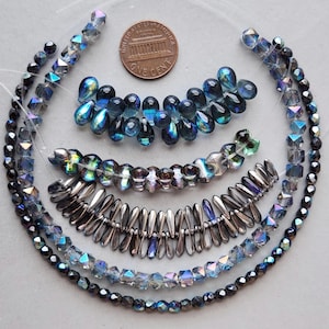 May include: An assortment of beads in various shapes and colors, including iridescent, blue, and silver. The beads are arranged in strands, with a penny for size comparison. The beads are suitable for jewelry making.