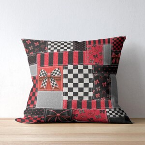 May include: A square throw pillow featuring a patchwork design of red, black, white, and gray panels. The pattern includes alternating sections of checkered squares, vertical stripes, and small bow motifs, with a prominent 3D-style bow graphic.