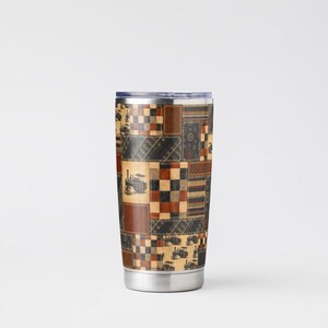 Peut inclure: Un gobelet cylindrique en acier inoxydable avec un motif patchwork compos&eacute; de carr&eacute;s marron, noirs et beige. Le design pr&eacute;sente des illustrations de tracteurs &agrave; vapeur anciens, des motifs &agrave; damier et des textures ray&eacute;es avec un couvercle transparent.