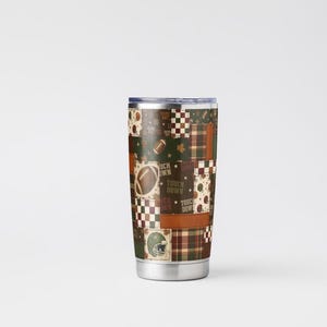 May include: A stainless steel tumbler with a patchwork design featuring footballs, helmets, and the words "Touch Down" in brown, green, and white. The tumbler has a silver base and a dark blue lid. The overall theme is sports.