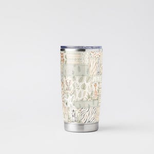 May include: A stainless steel travel tumbler with a patchwork design featuring safari animals and foliage in muted tones. The tumbler has a silver base and a dark blue lid, perfect for hot or cold beverages.