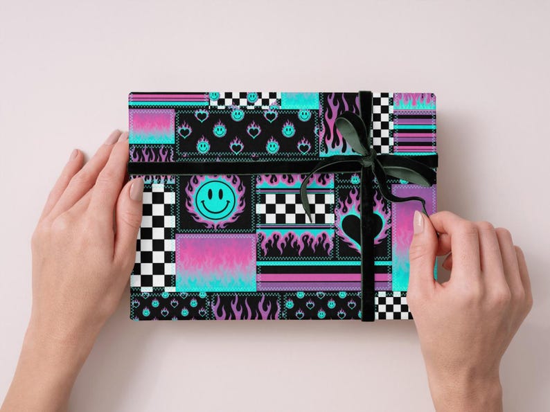 K&ouml;nnte beinhalten: Eine rechteckige Geschenkbox, eingewickelt in Papier mit einem Patchwork-Design aus schwarz-wei&szlig;em Schachbrettmuster, neonblauen Flammen, violetten Farbverl&auml;ufen und t&uuml;rkisfarbenen Smileys, gebunden mit einem d&uuml;nnen schwarzen Band.