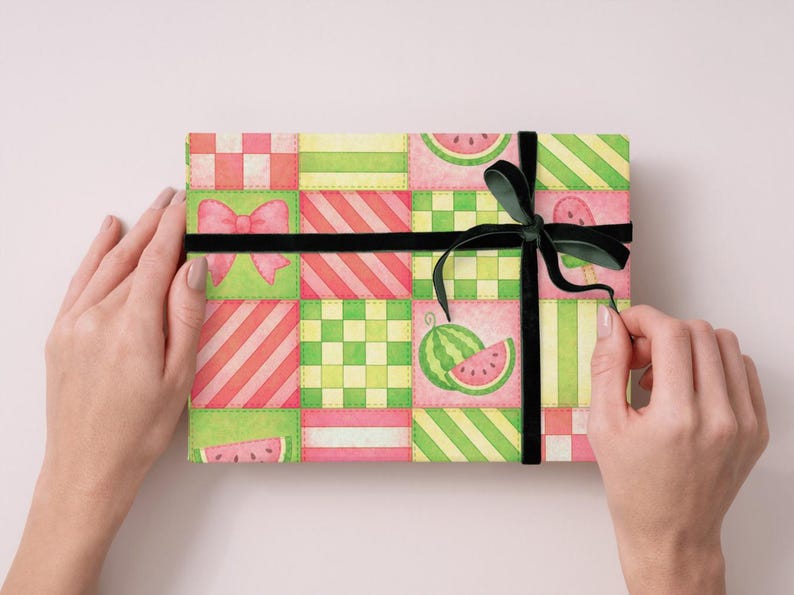 May include: A gift box wrapped in colorful paper with a watermelon pattern. The paper features a patchwork design with pink, green, and yellow squares, and is tied with a black ribbon and bow.
