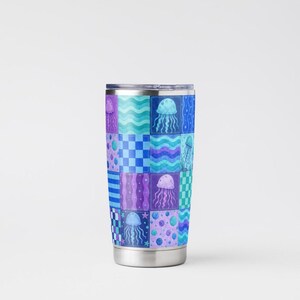 May include: A stainless steel travel mug with a patchwork design featuring jellyfish in shades of blue, purple, and teal. The pattern includes checkerboard, wavy lines, and polka dots. The mug has a silver rim and base.