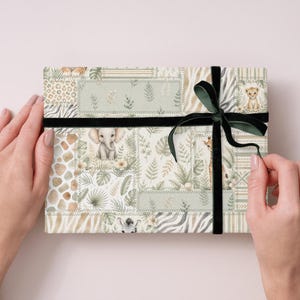 May include: A rectangular gift box wrapped in patterned paper with a safari theme, featuring illustrations of animals like elephants, giraffes, and zebras. The box is tied with a black velvet ribbon and a dark green bow.