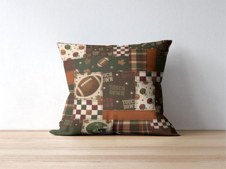 May include: Square decorative pillow with a patchwork design featuring footballs, helmets, and the words "Touch Down" on a brown, green, and orange background. The pillow has a plaid pattern and a solid green border.