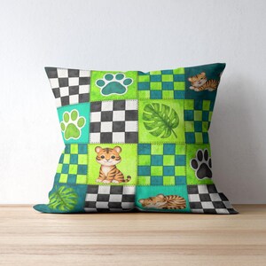 Peut inclure: Coussin carr&eacute; avec un motif patchwork repr&eacute;sentant des b&eacute;b&eacute;s tigres, des empreintes de pattes et des feuilles tropicales. Le coussin pr&eacute;sente un m&eacute;lange de carr&eacute;s verts, bleu sarcelle, noirs et blancs. Les b&eacute;b&eacute;s tigres sont orange et noirs.
