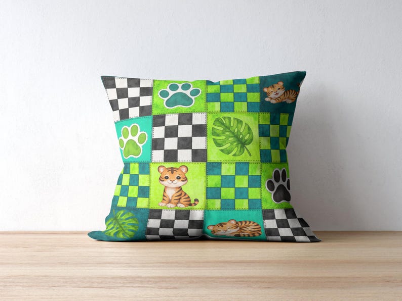 Peut inclure: Coussin carr&eacute; avec un motif patchwork repr&eacute;sentant des b&eacute;b&eacute;s tigres, des empreintes de pattes et des feuilles tropicales. Le coussin pr&eacute;sente un m&eacute;lange de carr&eacute;s verts, bleu sarcelle, noirs et blancs. Les b&eacute;b&eacute;s tigres sont orange et noirs.
