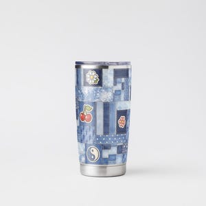 Op de afbeelding: Een roestvrijstalen beker met een patchwork denim design. De beker heeft verschillende patches met een madeliefje, kersen, een bloem en een yin-yang symbool. De beker is ongeveer 18 cm hoog.