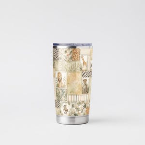 May include: A stainless steel travel tumbler with a patchwork design featuring various safari animals like lions, giraffes, and leopards. The tumbler has a silver base and a dark blue lid, perfect for hot or cold beverages.
