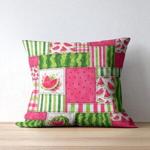May include: A square throw cushion featuring a patchwork design with various watermelon-themed patterns. The print includes bright pink sections with black seeds, green striped panels, and illustrations of sliced watermelon on a white background.