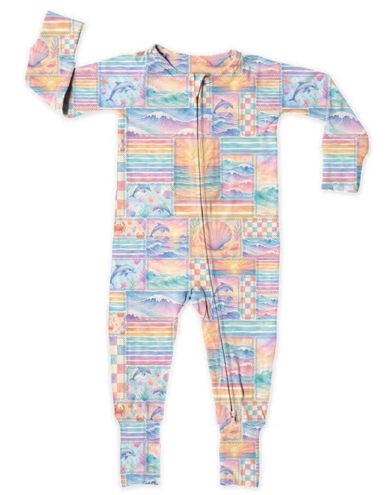 Pode incluir: Um pijama de beb&eacute; em tons pastel com fecho de correr. A pe&ccedil;a &uacute;nica apresenta um design de patchwork com ilustra&ccedil;&otilde;es com tema oce&acirc;nico, incluindo golfinhos, ondas, conchas e pores do sol. A paleta de cores inclui tons de azul, rosa, amarelo e laranja.