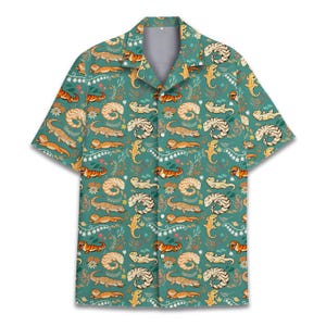 May include: Short-sleeved shirt with a teal background featuring a repeating pattern of lizards, flowers, and foliage in orange, cream, and white. The shirt has a classic collar and a relaxed fit, suitable for casual wear.