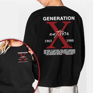 Op de afbeelding: Zwart sweatshirt met het woord "GENERATION" in witte blokletters boven een grote rode "X" afbeelding. De afbeelding bevat de tekst "es/1974", "1965" en "1980". Onder de afbeelding staat een lijst met tekst.