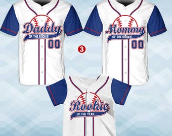 May include: Three white baseball jerseys with blue and red trim. The jerseys have the text "Daddy of the Rookie 00", "Mommy of the Rookie 00", and "Rookie of the Year" printed on them.