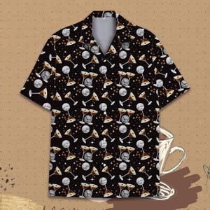 May include: Black short-sleeved shirt featuring a pattern of martini glasses, disco balls, and coffee beans. The shirt has a classic collar and a relaxed fit. The design incorporates brown, white, and silver elements, suitable for casual wear.