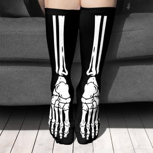 Könnte beinhalten: Schwarze Kniestrümpfe mit einem weißen Skelettknochen-Design. Die Socken sind aus einem weichen, bequemen Material gefertigt und perfekt für Halloween.