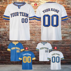 Può includere: Maglia da baseball bianca con dettagli blu e oro. Sul davanti c'è scritto "YOUR TEAM" e "00". Sul retro c'è scritto "YOUR NAME" e "00". Sono mostrate anche altre maglie blu e bianche con design simili.