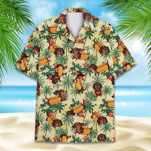 Könnte beinhalten: Kurzärmeliges Button-Down-Hemd mit einem sich wiederholenden Muster aus Dackeln in Hotdog-Brötchen, Palmen und Blumen. Das Hemd hat einen hellgelben Hintergrund mit blauem Ozean und Himmel im Hintergrund.