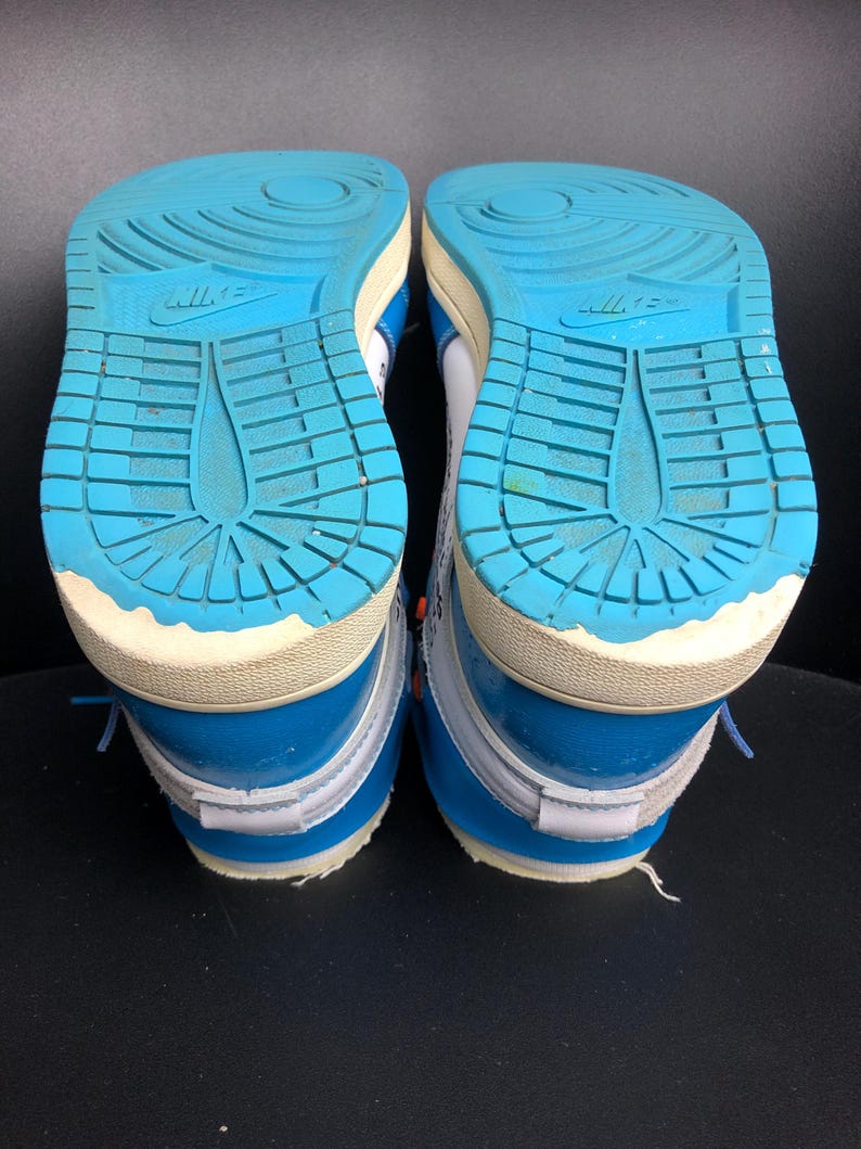 K&ouml;nnte beinhalten: Paar blaue und wei&szlig;e Turnschuhe mit hellblauen Sohlen. Die Sohlen haben ein strukturiertes Muster und das Nike-Logo. Die Schuhe haben blaue Schn&uuml;rsenkel und wei&szlig;e Akzente.