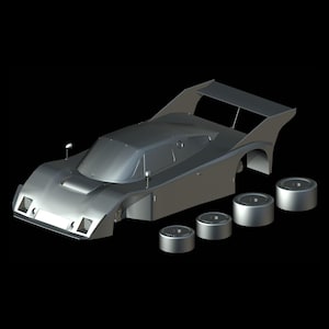 Puede incluir: Un modelo de coche de carreras plateado con alerón trasero y cuatro ruedas separadas. El coche tiene un diseño elegante y aerodinámico con un perfil bajo y una cabina. Las ruedas son cilíndricas.