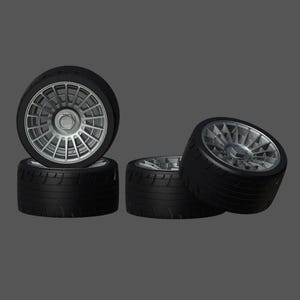 May include: Four black tires with silver spoke wheels. The tires are stacked on top of each other.