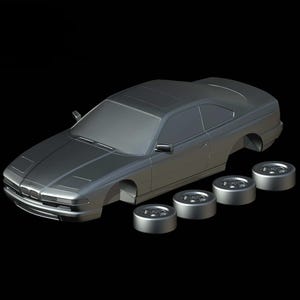 Puede incluir: Un modelo de coche plateado con cuatro ruedas separadas. El coche tiene un diseño cupé con techo solar y faros detallados. Las ruedas también son plateadas y tienen un diseño de radios múltiples. El fondo es negro.
