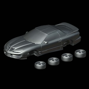 May include: A gray model car chassis with four black wheels. The car is a sports car with a sleek design. The car is missing its body panels and interior.