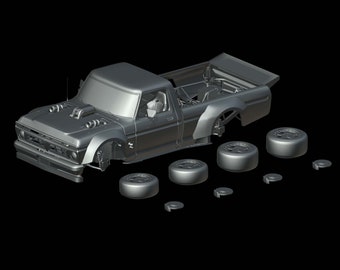 Op de afbeelding: Een gedemonteerde model autokit van een grijze pick-up truck met een zwart interieur. De kit bevat de carrosserie van de truck, wielen en andere onderdelen.