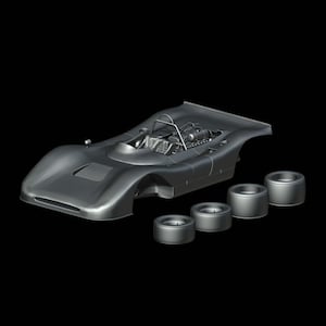 Può includere: Un modello di auto da corsa color argento con un motore dettagliato e un roll-bar. La carrozzeria dell'auto è aerodinamica e quattro ruote separate sono posizionate nelle vicinanze. Il modello è su sfondo nero.