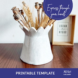 May include: White ceramic vase with a scalloped rim, filled with dried poppy seed pods and wheat stalks. The vase is sitting on a wooden table. The text "Express through your hands" is visible in a blue circle above the vase.