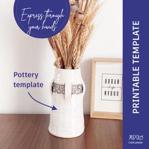 Puede incluir: Jarrón de cerámica blanca con un esmalte moteado y un diseño geométrico negro. El jarrón está lleno de tallos de trigo secos y tiene una superposición de texto que dice "Exprésate a través de tus manos" y "Plantilla de cerámica".