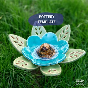 May include: A ceramic flower sculpture featuring light green leaves with cut-out details and a bright turquoise petal layer. The center is a raised, textured brown and gold dome. The text POTTERY TEMPLATE is visible above the object.