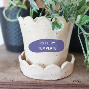 May include: A cream-colored ceramic planter with a speckled finish and a scalloped rim, accompanied by a matching scalloped saucer. The front of the planter features a purple oval graphic with the white text POTTERY TEMPLATE printed on it.