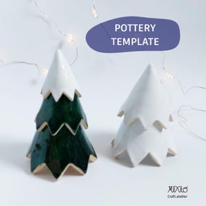 以下が含まれることがあります： 2つのセラミッククリスマスツリーの置物。1つは白と金のアクセントが付いた濃い緑色で、もう1つは金色のアクセントが付いた白色です。木は層状のデザインで、白い背景に配置されています。「POTTERY TEMPLATE」というテキストが青い楕円の中にあります。
