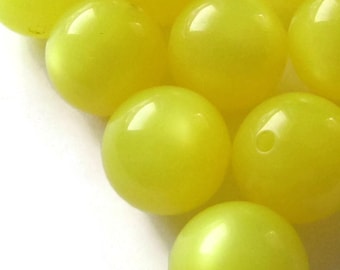 Puede incluir: Un grupo de 12 cuentas redondas de color amarillo brillante. Las cuentas son lisas y brillantes.