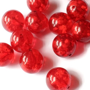 May include: A group of red glass beads with a speckled finish. The beads are round and have a glossy finish.