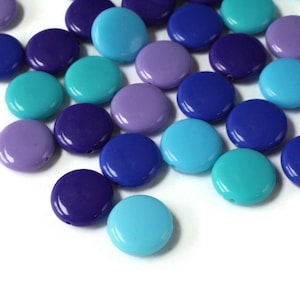 May include: A collection of round, flat, plastic beads in shades of blue, purple, and teal.