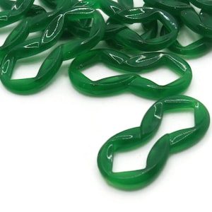 May include: A pile of green plastic chain links. Each link is shaped like a figure eight with a diamond-shaped hole in the center.