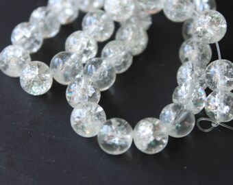 Può includere: Una collana di perline di vetro trasparente con riflessi iridescenti. Le perline sono rotonde e hanno una superficie leggermente ruvida.