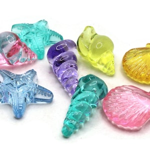 May include: Assortment of colorful glass sea life charms, including starfish, seashells, and spiral shells. The charms are translucent and have a variety of colors, including pink, blue, yellow, and purple.