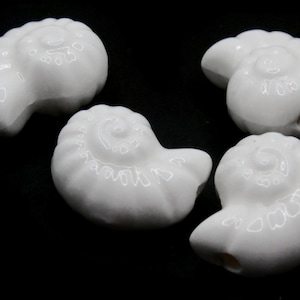 以下が含まれることがあります： 貝殻の形をした白いセラミックビーズが4つ。ビーズは滑らかで光沢があり、らせん状のデザインが施されています。