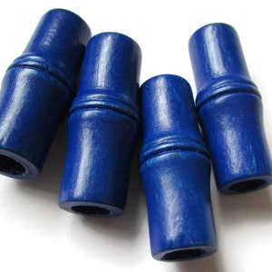 May include: Four blue wooden beads with a bamboo-like design. The beads are smooth and have a glossy finish.