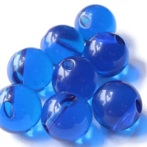 May include: A group of eight blue glass beads, each with a hole in the center. The beads are arranged in a pyramid shape, with the largest bead at the top and the smallest beads at the bottom.