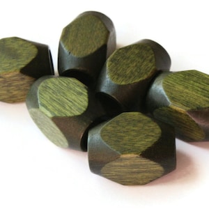May include: Six hexagonal wooden beads in a dark green color. The beads have a slightly rough texture and are arranged in a pile.