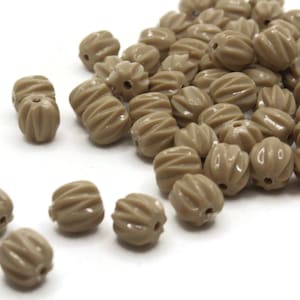 May include: A pile of brown plastic beads with a ribbed texture. The beads are oval shaped and have a hole in the center.